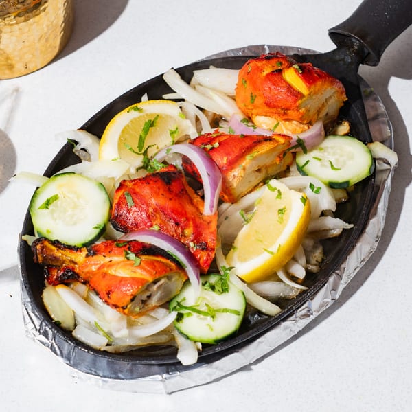 Tikka Tikka Indian Cuisine's chicken tikka sizzler with onions, lemons, and cucumbers.